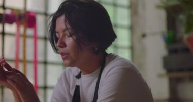 Kadın çiçekçi üzgün bir şekilde kırsal çiçekçi dükkanına bakıyor, küçük işletme sahibi duygusal yorgunluk ve iş baskısı hissediyor.