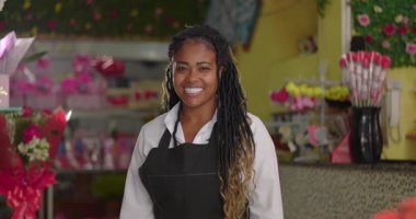 Çiçekçi dükkanında gülümseyen Afrikalı Amerikalı çiçekçi, kendine güvenen işyeri sahibi çiçekçi dükkanında duruyor.
