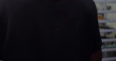 Önlüklü Afrikalı Amerikalı fırın işçisi ticari mutfağın içindeki metal raflara taze ekmek koyuyor.