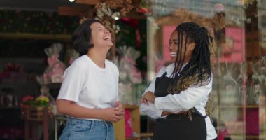 Çiçekçiler butik çiçekçinin önünde gülüp sohbet ediyorlar. Sıcak ve hoş geldin mağazasındaki iş arkadaşları arasındaki dostluk ve sohbet anı.