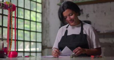 Not defterine yazan kadın çiçekçi ve kırsal çiçekçi dükkanında düşünen küçük işletme sahibi gelecekteki yaratıcı fikirleri ve girişimcilik projelerini planlıyor.