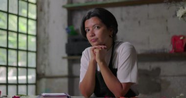 Tezgahta oturan kadın çiçekçi kırsal kesimdeki çiçekçinin içinde düşünceli görünüyor, küçük işletme sahibi gelecek fırsatları ve iş büyümesini düşünüyor.