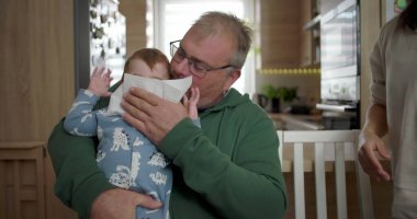 Çocuğun yüzünü bez parçasıyla silen baba şefkatli bir aile ortamında şefkat ve şefkat gösteriyor..