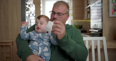 Çocuğun yüzünü bez parçasıyla silen baba şefkatli bir aile ortamında şefkat ve şefkat gösteriyor..