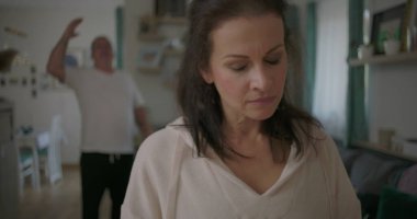 Tartışma sırasında ön planda aşağılanmış ifadeyle duran kadın, arka planda hayal kırıklığı, duygusal ve gergin ilişki çatışması içinde hareket eden erkek.