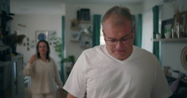 Oturma odasında tartışan bir erkek, duygusal ve gergin bir tartışmaya giren bir çift, vücut diline ve yoğun iletişime odaklanıyor.