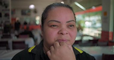 Latin bayan garson, restoranda duruyor, uzak bakışlarla çenesini dinlendiriyor, öğlen vardiyasında düşünceli bir ruh hali sergiliyor.