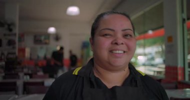 Yemek alanında gülümseyen Latin lokantası çalışanı, arkadaş canlısı tavırlar ve kapalı mekan restoranlarında olumlu vücut dili.