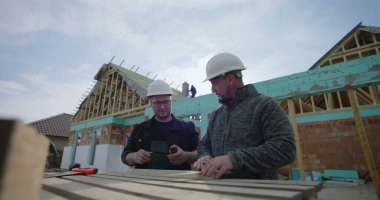 İnşaat alanındaki odunları ölçen müteahhitler, işbirliği çabası, hassas ölçümler, ev iskeleti, takım çalışması, konut projesi, başlıklar, görünür araçlar