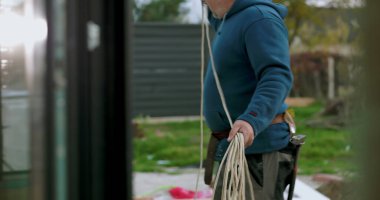 İnşaat sahasında miğferi olan işçilere kablo taşıyıp düzenlemek, el işçiliği ve dışarıda profesyonel aktiviteler sergilemek.