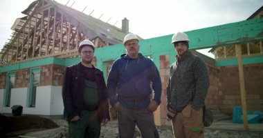 İnşaat alanında poz veren inşaat ekibi, proje alanında bir araya gelen inşaat profesyonelleri grubu, inşaat sektöründe takım çalışması ve işbirliği