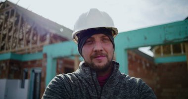 İnşaat alanında çalışan erkek inşaat işçisinin yakın plan portresi, kameraya bakan kendine güvenen profesyonel, endüstri uzmanlığı ve adanmışlığına odaklan
