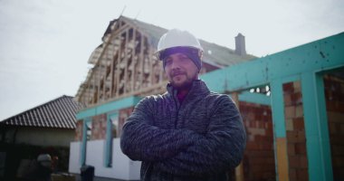 İnşaat alanında çalışan erkek inşaat işçisinin yakın plan portresi, kameraya bakan kendine güvenen profesyonel, endüstri uzmanlığı ve adanmışlığına odaklan