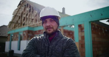 İnşaat alanında çalışan erkek inşaat işçisinin yakın plan portresi, kameraya bakan kendine güvenen profesyonel, endüstri uzmanlığı ve adanmışlığına odaklan