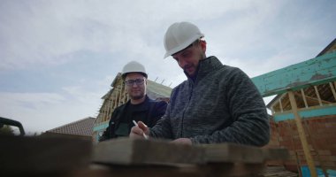 İnşaat alanındaki odunları ölçen müteahhitler, işbirliği çabası, hassas ölçümler, ev iskeleti, takım çalışması, konut projesi, başlıklar, görünür araçlar