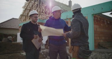 Bina planlarını inceleyen inşaat ekibi, inşaat planlarına odaklanmış tartışma, proje yönetiminde işbirliği, iş başında inşaat sektörü profesyonelleri