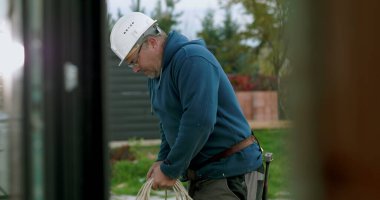 İnşaat sahasında miğferi olan işçilere kablo taşıyıp düzenlemek, el işçiliği ve dışarıda profesyonel aktiviteler sergilemek.