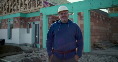 İnşaat işçisi inşaat alanında çalışıyor, devam eden projenin önünde profesyonel poz veriyor, şanlı inşaat işçisi iş yerinde çalışıyor, kararlılık ve gurur.