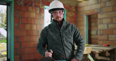 Metal kesme görevi, güvenlik kaskı ve koruyucu gözlük için hazır olan inşaat işçisi, görünür alet ve ekipman ile kapalı inşaat alanı kurulumu