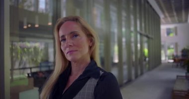 Koridorda dik dik bakan kadın, modern çalışma ortamında otorite güveni ve kendine güveni aktarıyor.