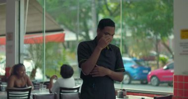 Restoran çalışanı yüzünü pencereye yakın tutuyor. Yorgunluk, duygusal yorgunluk ve aşırı yorgunluk belirtileri gösteriyor.