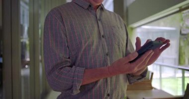 Ofis koridorunda cep telefonu kullanan orta yaşlı bir adam modern iş ortamında cep telefonuyla meşgul oluyor.