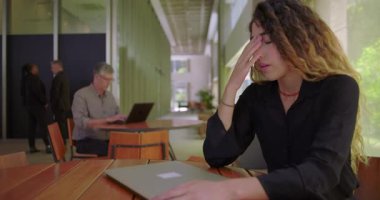 Ofis masasında kafası kapalı bir dizüstü bilgisayarda dinlenen kadın, tamamen bitkin ve iş stresi ve tükenmişlik yüzünden duygusal olarak tükenmiş.