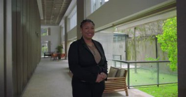 Afro-Amerikalı bir kadın cam pencerelerin yanındaki geniş koridorda el ele tutuşarak liderlik ve profesyonelliği içtenlikle temsil ediyor.