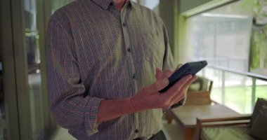 Ofis koridorunda cep telefonu kullanan, ekranı dinleyen ve iş ortamında mobil teknolojiyle etkileşime geçen orta yaşlı adamların ellerini kapatın.