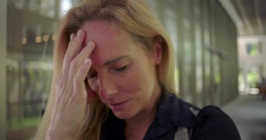 Başı öne eğik ve eli alnında, duygusal yükü ya da derin stresi ifade eden bir kadına yaklaşın.