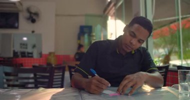 Restoran işçisi masaya notlar yazıyor, Latin Amerika 'nın günlük yemek dükkanının içindeki sakin ve odaklı atmosfer.