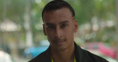 Latin Amerikalı adamın yakın plan portresi. Restoranın içindeki kameraya sakince bakıyor. Pencerenin yanında duruyor.