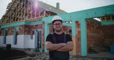 İnşaat işçisi inşaat alanında kollarını kavuşturmuş, inşaat sektöründe kendine güvenen, sorumluluk sahibi ve gururlu bir inşaat işçisi, devam etmekte olan bir proje.