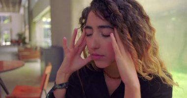 Kapalı gözlü stresli kadın şakaklara dokunuyor, ofis ortamında bunalmış ve bitkin hissediyor, iş yerinde bitkinlik ve ruh sağlığı teması