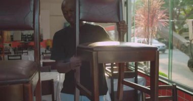 Latin Amerika Lokantası 'ndaki personel, çalışma saatinin başında sandalyeleri indirerek yemek alanı kuruyor.