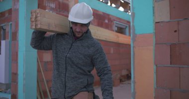 İnşaat işçisi, inşaat alanında odun, takım çalışması ve güç taşıyor, konut inşaatı projesi devam ediyor, kendini işine adamış ve sıkı çalışıyor.