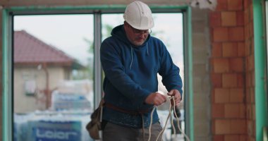 Mavi kapüşonlu inşaat işçisi halatlar, başlık, inşaat alanı, bina içi inşaat, hazırlık aletleri, yenileme işine odaklan.