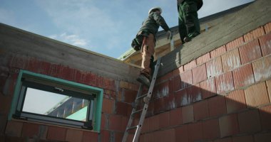 İnşaat işçisi inşaat alanının çatısından inen merdiven, güvenlik ve ekip çalışması vurgulandı, açık hava konut inşaat projesi devam ediyor