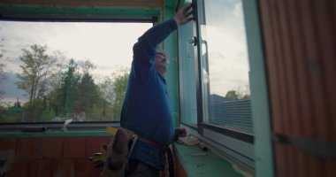 İnşaat işçisi inşaat alanındaki pencere hizasını denetliyor, başlık takıyor ve konut projesinde kalite kontrolü için çerçeve ayarlıyor