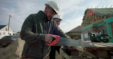 Derme çatma tezgahta odun kesen inşaatçı, arka plandaki bina, göreve odaklanmış, yapım aşamasındaki yapı, iş başında yetenekli işçilik