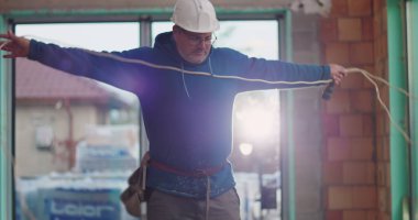 Mavi kapüşonlu inşaat işçisi halatlar, başlık, inşaat alanı, bina içi inşaat, hazırlık aletleri, yenileme işine odaklan.