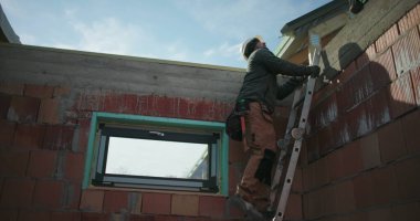 İnşaat işçisi inşaat alanının çatısından inen merdiven, güvenlik ve ekip çalışması vurgulandı, açık hava konut inşaat projesi devam ediyor