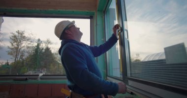 Pencere kurulumunu denetleyen inşaat işçisi, uygun ve seviye aracı ile aynı hizayı sağlama, inşaat alanında odaklanmış profesyonel pencere ayarları