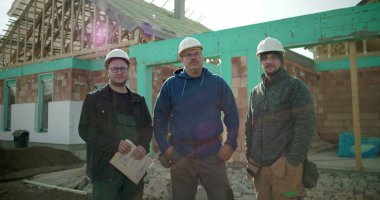 İnşaat işçileri inşaat sahasında birlikte duruyorlar. İnşaat projesi, birlik ve inşaat sektöründe çalışan profesyonellerden oluşan bir ekip.