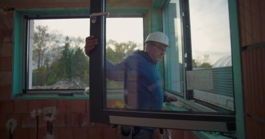 İnşaat alanındaki pencere çerçevesini ayarlayan işçiler, konut inşaatı projesinde doğru kurulum olup olmadığını kontrol ediyorlar, kalite kontrol odağı