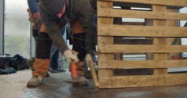 İnşaat alanının zemininde ahşap paleti ayarlayan işçiler, el emeği, el işi, el işi, inşaat malzemeleri, iş başında takım çalışması, aktif inşaat ortamı