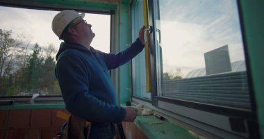 Pencere kurulumunu denetleyen inşaat işçisi, uygun ve seviye aracı ile aynı hizayı sağlama, inşaat alanında odaklanmış profesyonel pencere ayarları