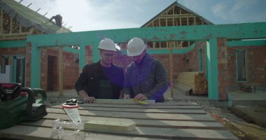 Konut inşaatı projesinde ahşabı ölçen ve işaretleyen mimarlar, takım çalışması ve hassasiyeti, işe yarar araçlar, ev iskeleti gelişimi