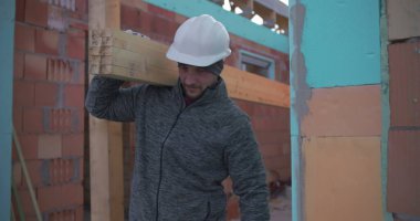 İnşaat işçisi, inşaat alanında odun, takım çalışması ve güç taşıyor, konut inşaatı projesi devam ediyor, kendini işine adamış ve sıkı çalışıyor.