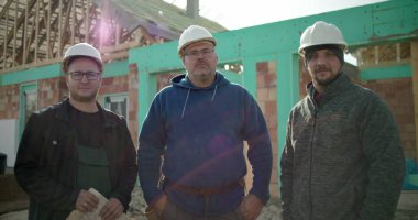 İnşaat işçileri inşaat sahasında birlikte duruyorlar. İnşaat projesi, birlik ve inşaat sektöründe çalışan profesyonellerden oluşan bir ekip.